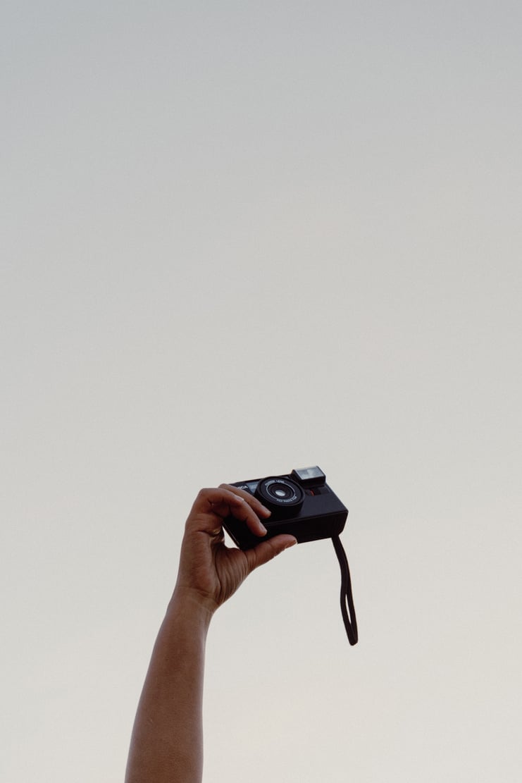 Person's Hand Holding a Vintage Camera against the Sky